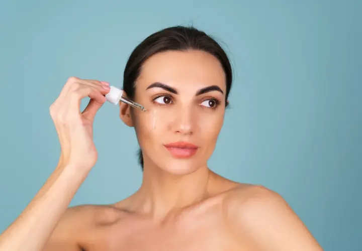 Kvinnan applicerar serum med retinol ansikte.