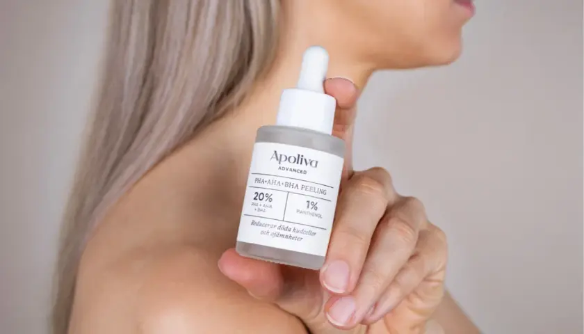 En hand håller en flaska med Apoliva PHA+AHA+BHA Peeling, perfekt för att behandla **peeling ansikte torr hy**.