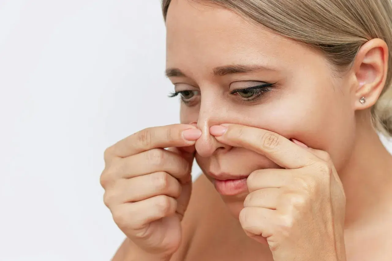 En kvinna undersöker sin näsa, där en pormask som fylls på syns tydligt.