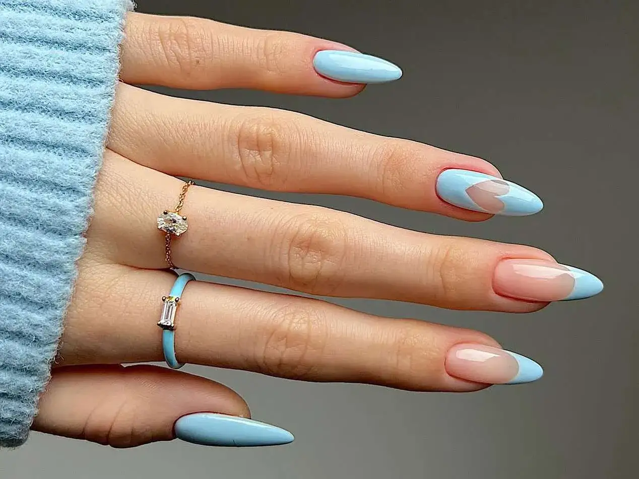 Vacker ljusbl&aring; avril nagellack med hj&auml;rtm&ouml;nster och fransk manikyr. Tv&aring; ringar pryder fingrarna.