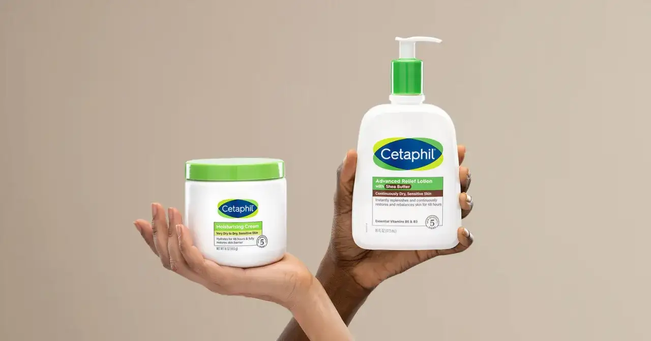 Två händer håller upp Cetaphil-produkter. En hand håller en burk med återfuktande kräm, den andra en flaska med body lotion i ansiktet.
